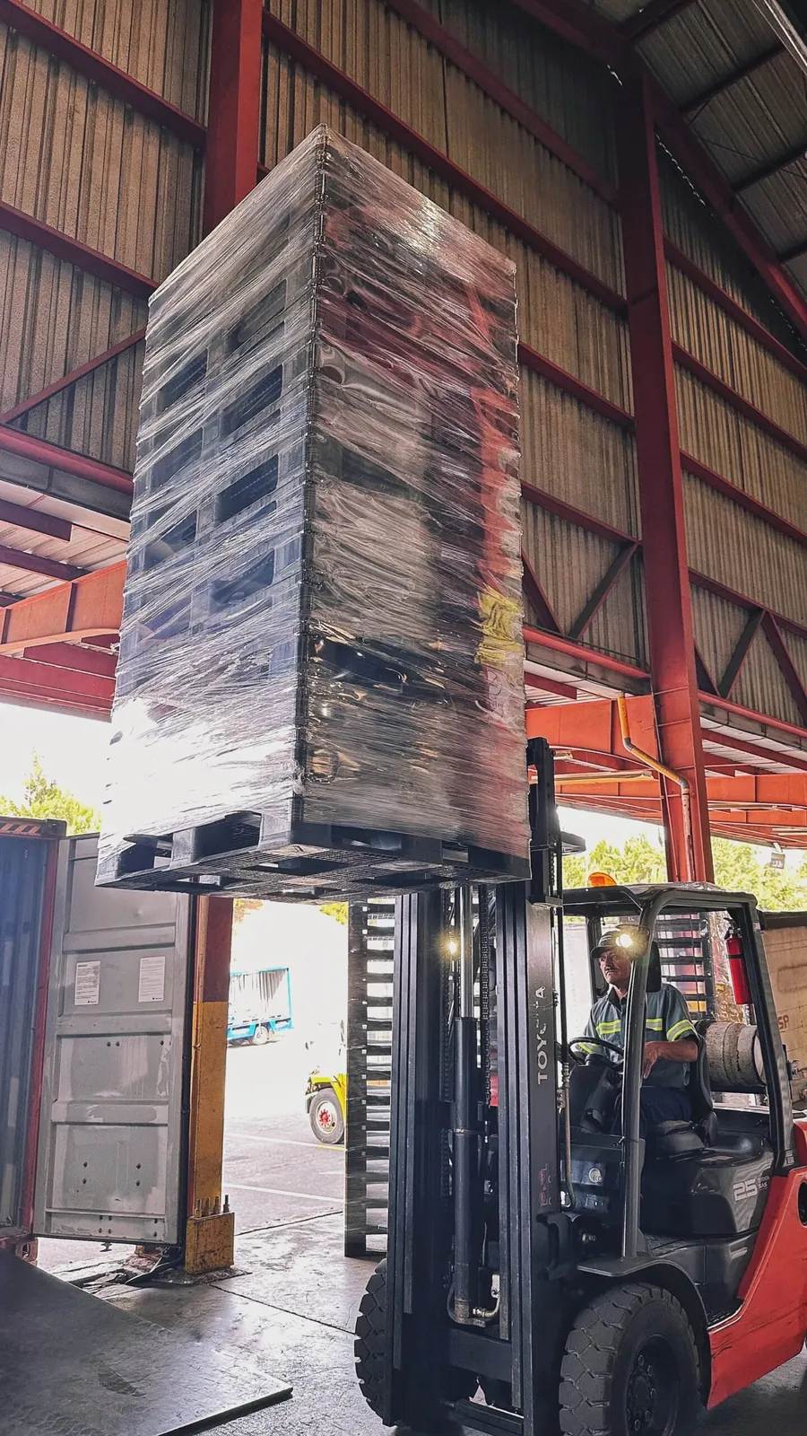 Montacargas cargando un contenedor con pallets plásticos